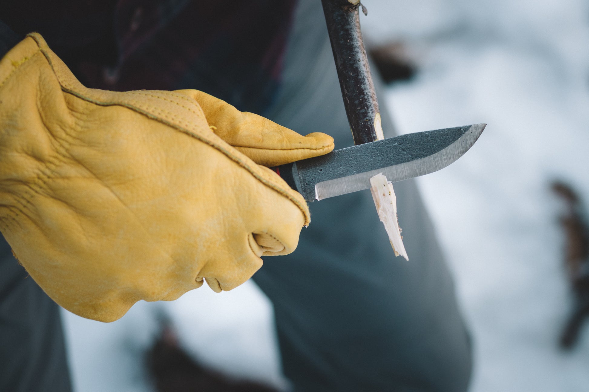 Yellow glove holding a knife with a blurred background